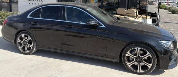 Black Mercedes E-Class taxi parked at a marina office in Trogir