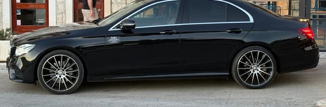 Black Mercedes E-Class taxi on the stone waterfront outside a Trogir hotel